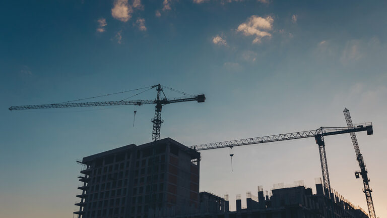 construction of the building cranes in the strongest light, otherwise. crane building in sunset sky. The architectural complex of residential buildings on sky background